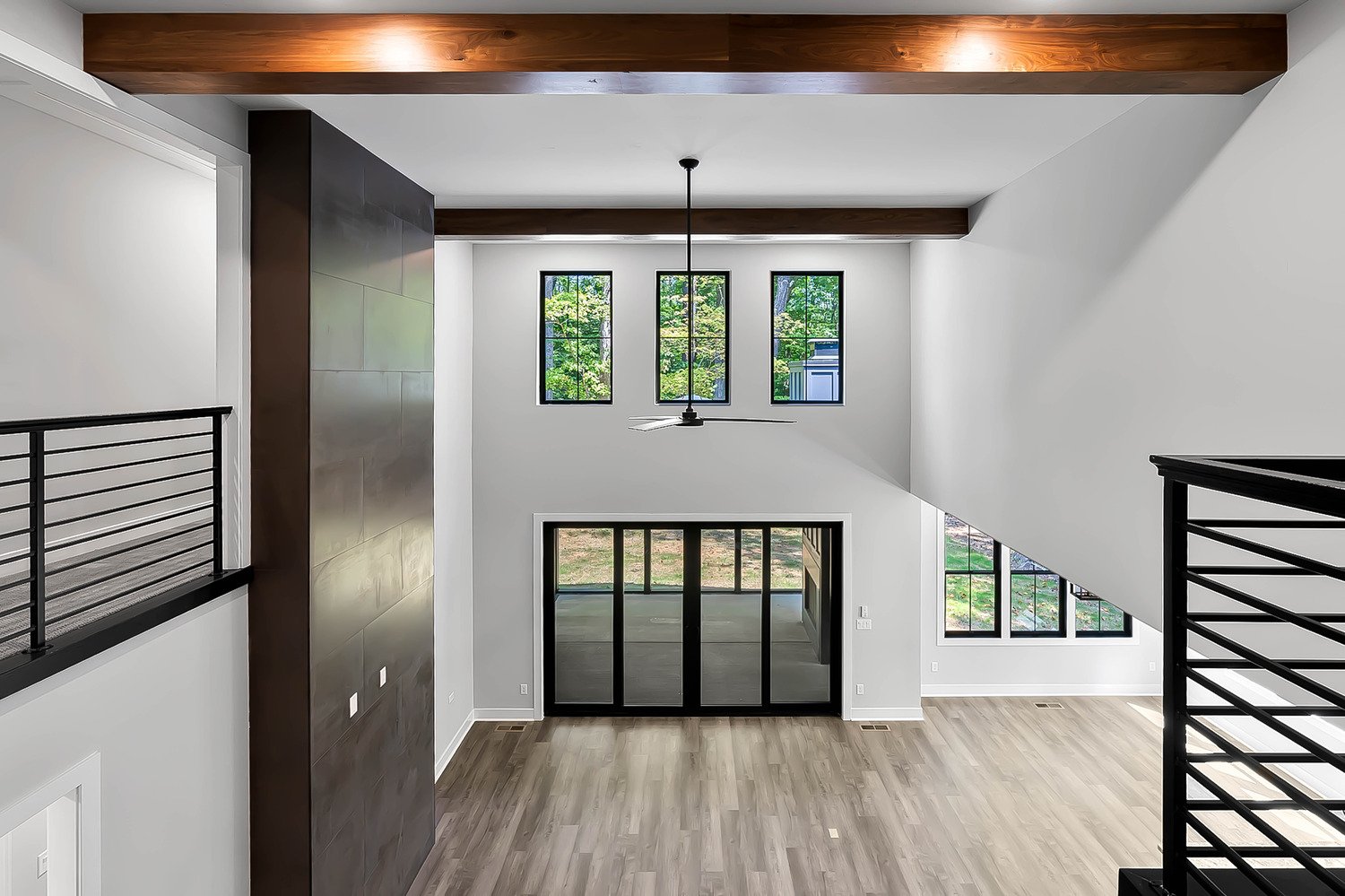 Spacious modern living room with tall windows and ceiling beams, photographed by Raleigh real estate photographer R. Huggins