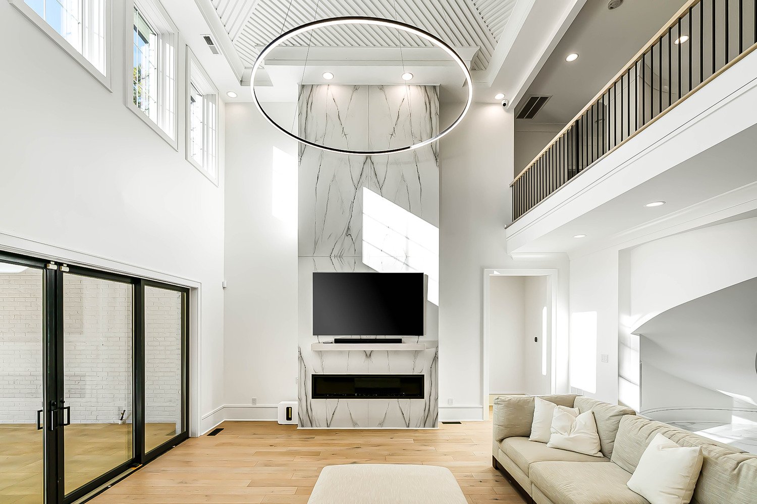 Contemporary living room with marble fireplace and statement lighting, photographed by R. Huggins, Raleigh real estate media expert