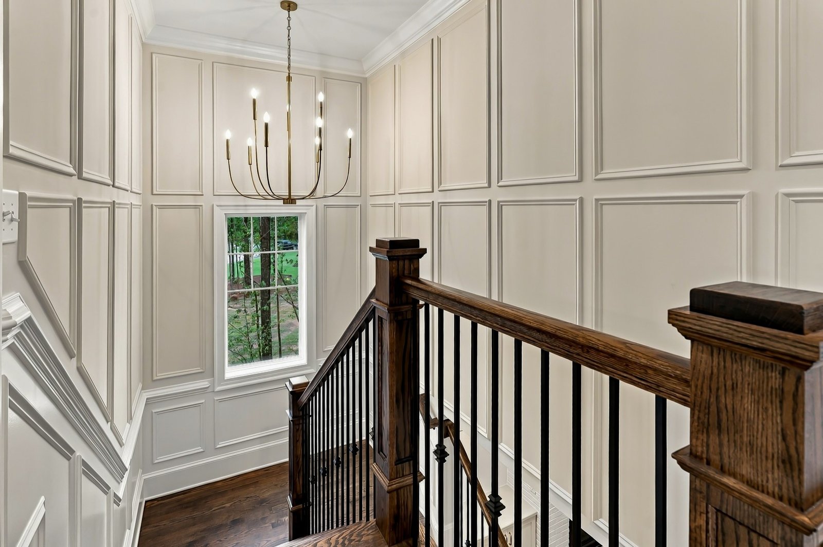 Elegant panelled staircase with wood railing and chandelier, interior real estate photography by R. Huggins